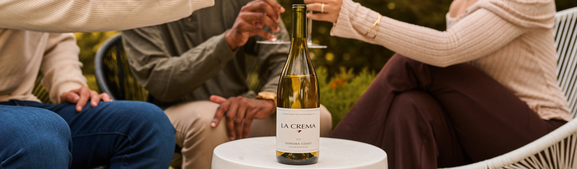 A group of friends drinking a bottle of La Crema Chardonnay wine